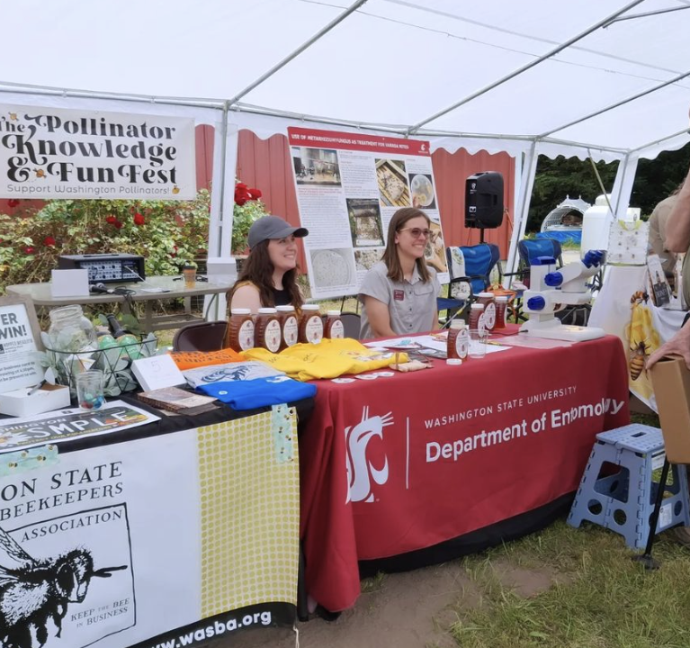 people sitting at WSU bee program booth